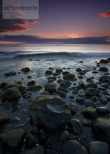 Rosa Wolken bei Sonnenuntergang mit der Brandung  die an die Felsen entlang der Küste einer hawaiianischen Insel rollt; Hawaii  Vereinigte Staaten von Amerika'.