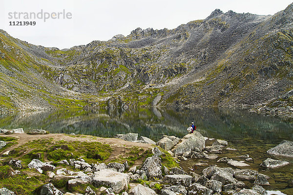 Zwei Wanderer halten an  um die Aussicht am Gold Cord Lake am Hatcher Pass zu genießen. Südzentrales Alaska. Sommer.