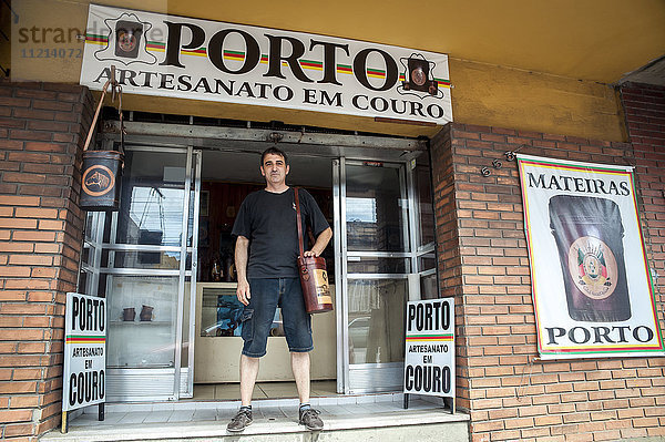 Ein Mann steht in der Tür eines Ladens und hält eine handgefertigte Ledertasche; Pelotas  Rio Grande do Sul  Brasilien