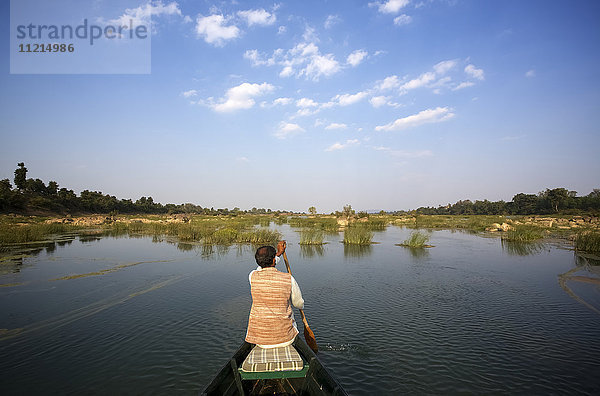 Bootsführer paddelt auf einem ruhigen Fluss am frühen Morgen