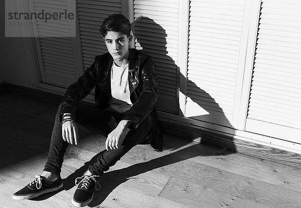 Ein junger Mann in einer schwarzen Lederjacke sitzt auf dem Boden und schaut nach oben; Tarifa  Cadiz  Andalusien  Spanien'.