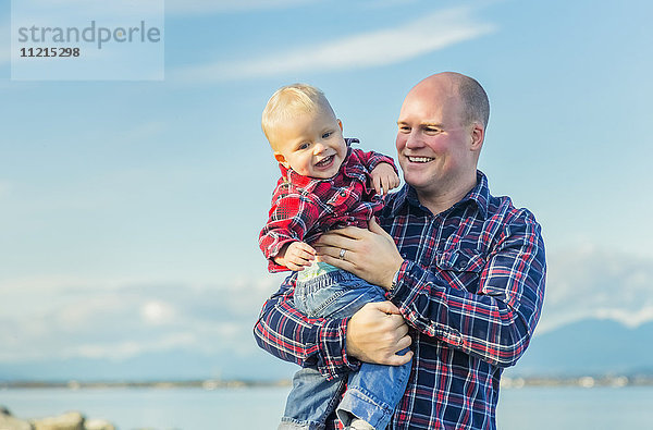 Ein Kleinkind und sein Vater spielen zusammen am Strand an einem sonnigen Tag an der Westküste Kanadas; Surrey  British Columbia  Kanada'.