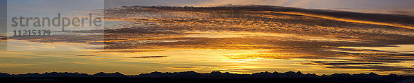 Panorama von farbenfrohen  dramatischen Wolken bei Sonnenuntergang mit der Silhouette von Bergen am Horizont; Calgary  Alberta  Kanada'.