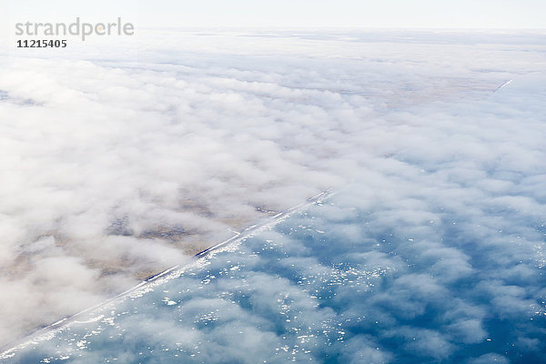 Luftaufnahme der in eine dünne Wolkenschicht gehüllten North-Slope-Küste  im Arktischen Ozean treibende Eisberge; Deadhorse  Alaska  Vereinigte Staaten von Amerika'.