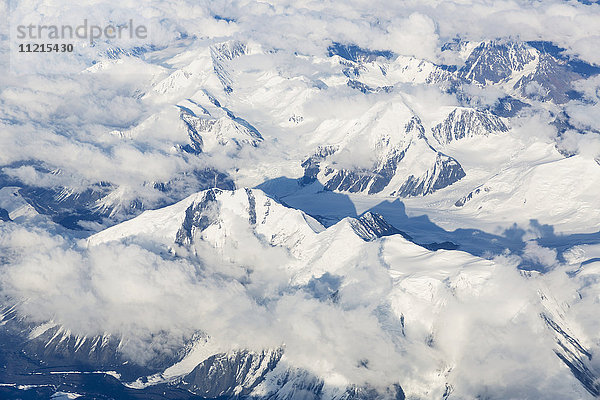 Luftaufnahme von Wolken  die sich zwischen den schneebedeckten Gipfeln der Alaska Range winden  im Inneren Alaskas; Alaska  Vereinigte Staaten von Amerika'.