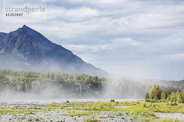 Flussschlick  der an einem windigen und bewölkten Tag über das Flussbett des Matanuska River geweht wird  King Mountain im Hintergrund  Süd-Zentral-Alaska im Sommer; Palmer  Alaska  Vereinigte Staaten von Amerika'.