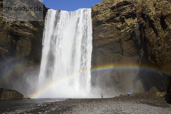 Hoher Wasserfall  der von einer Felsklippe herabstürzt  mit Gischt-Regenbogen i