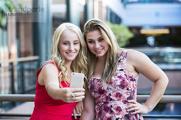 Zwei schöne junge Frauen machen ein Selbstporträt während einer Pause an ihrem Arbeitsplatz; Edmonton  Alberta  Kanada'.