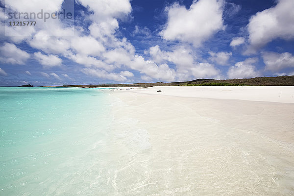 Weißer Sandstrand mit kristallklarem  türkisfarbenem Wasser und blauem Himmel