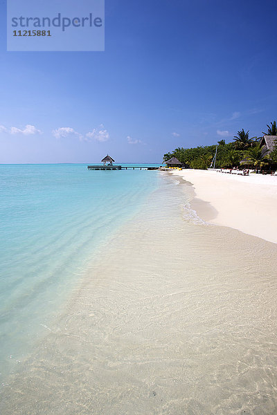 Klassischer weißer Sandstrand mit blauem Meer und Überwasser-Cabana