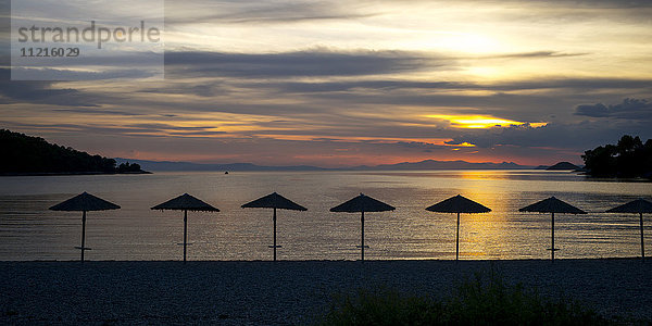 Silhouette von Sonnenschirmen am Strand bei Sonnenuntergang auf einer griechischen Insel im Ägäischen Meer; Panormos  Thessalia Sterea Ellada  Griechenland'.