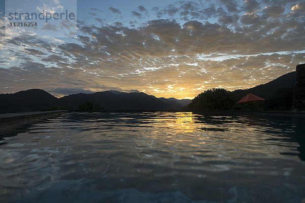 Sonnenlicht  das sich bei Sonnenuntergang auf dem ruhigen Meerwasser spiegelt; Jalisco  Mexiko'.
