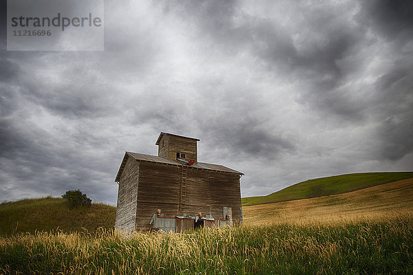 Eine alte Holzscheune in einem Feld mit sanften Hügeln unter Gewitterwolken; Palouse  Washington  Vereinigte Staaten von Amerika'.
