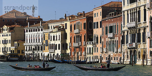Bunte Gebäude entlang eines Kanals mit Gondolieri in Gondeln; Venedig  Italien