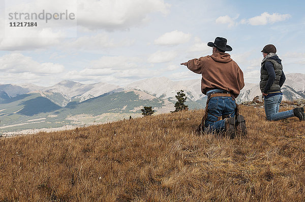 Cowboy und eine Frau auf den Knien mit Blick auf die felsigen Berge  Ya-Ha-Tinda Ranch; Alberta  Kanada