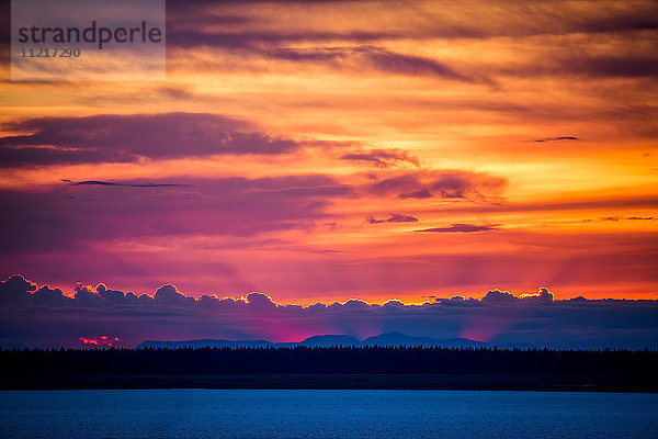 Licht leuchtet hinter Wolken und Bergen bei Sonnenuntergang; Anchorage  Alaska  Vereinigte Staaten von Amerika'.