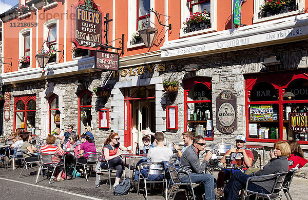 Kunden sitzen auf der Terrasse eines Restaurants an einer Straße; Kenmare  County Kerry  Irland