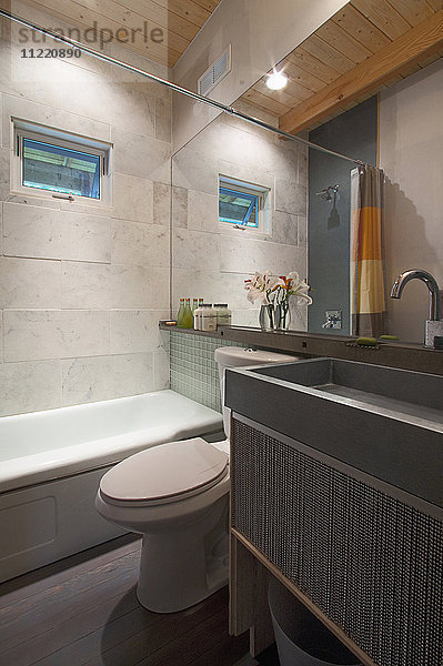 Modernes Badezimmer mit Badewanne und Waschbecken am Spiegel