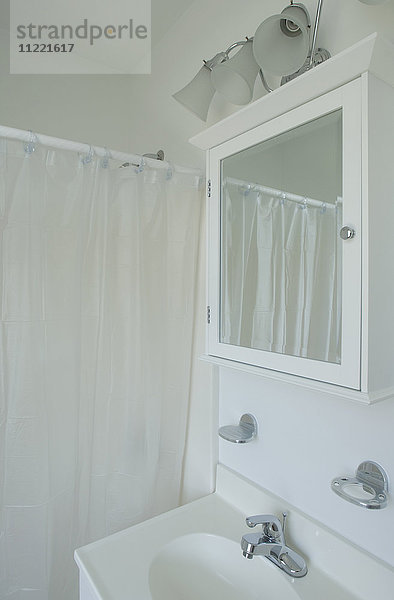 Weißes Waschbecken  Medizinschrank und Duschvorhang