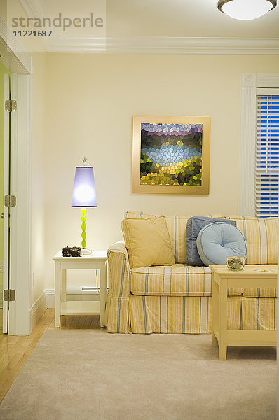 Lila Lampe auf Beistelltisch neben gelb und blau gestreiftem Sofa