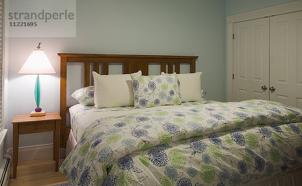 Bett im Schlafzimmer mit blauer und grüner Bettdecke