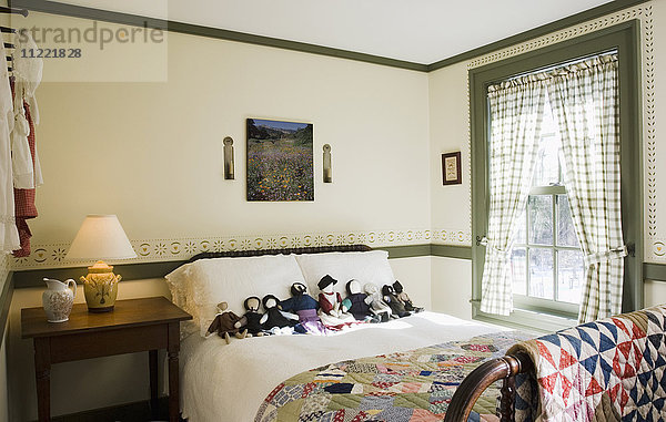 Kleines Schlafzimmer im Kolonialstil mit einer Sammlung von amischen Puppen auf dem Bett