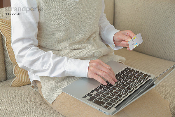 Modische japanische Seniorin bei der Arbeit mit Laptop