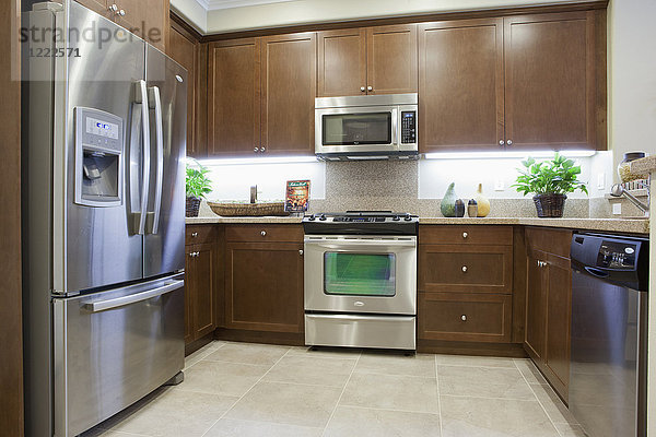 Küche mit braunen Schränken und Kühlschrank aus Edelstahl zu Hause