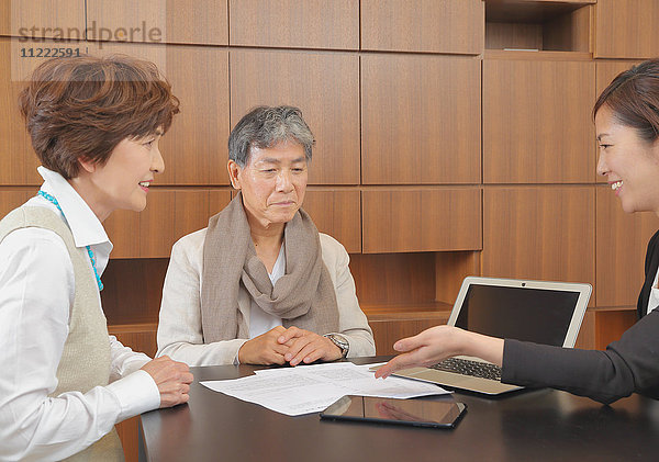 Modisches japanisches Seniorenpaar im Gespräch mit Beraterin