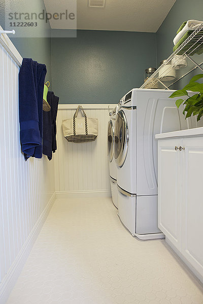 Waschmaschinen mit an der Wand hängenden Handtüchern in der Waschküche