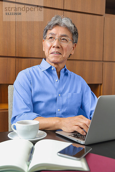 Modischer japanischer älterer Mann bei der Arbeit