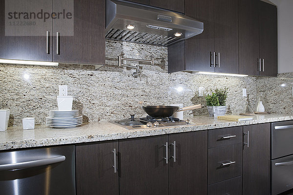 Küche mit braunen Schränken mit Granit Arbeitsplatte und Wand zu Hause
