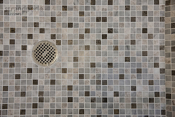 Nahaufnahme des Abflusses im Mosaikfliesenboden im Badezimmer zu Hause