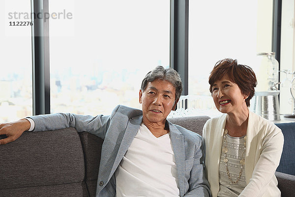 Modisches japanisches Seniorenpaar auf dem Sofa