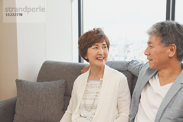 Modisches japanisches Seniorenpaar auf dem Sofa
