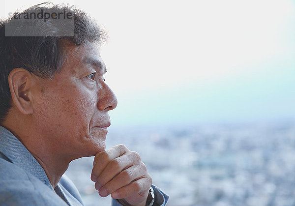Modischer japanischer älterer Mann mit Blick auf das Stadtbild von Tokio