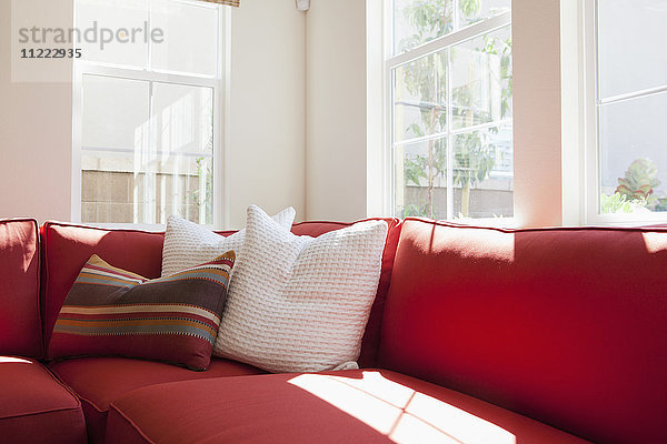 Geschnittene rote Couch mit Kissen im Wohnzimmer zu Hause
