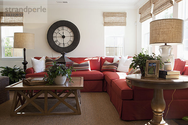 Modernes Wohnzimmer mit rotem Sektionssofa und großer Wanduhr zu Hause