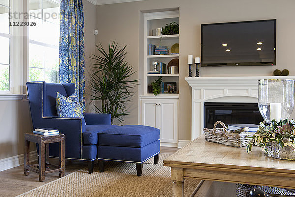 Flachbildfernseher über dem Kamin mit blauer Chaiselongue im Wohnzimmer zu Hause
