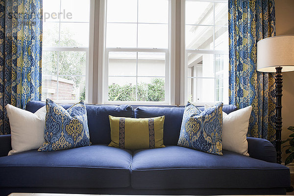 Nahaufnahme von Kissen auf blauen Couch gegen Fenster im Wohnzimmer zu Hause