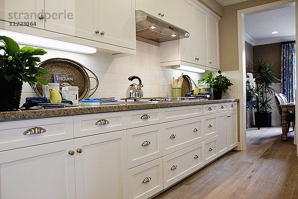 Küche mit weißen Schränken und Holzboden zu Hause