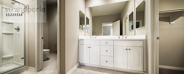 Badezimmer mit abgeschnittener Kommode und Waschbecken mit Schränken am Spiegel