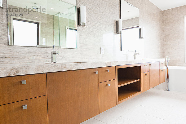 Zeitgenössisches Badezimmer mit braunen Schränken am Spiegel