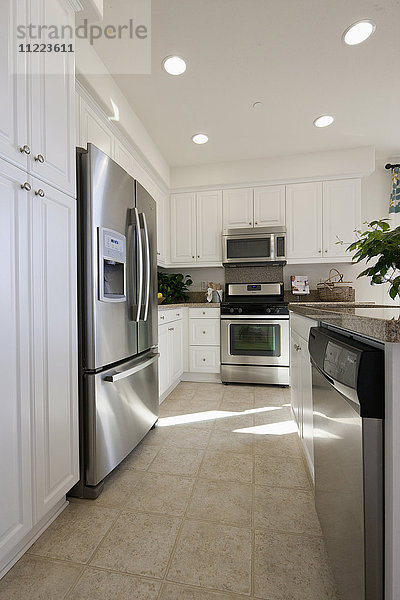 Küche mit weißen Schränken und Kühlschrank aus Edelstahl zu Hause