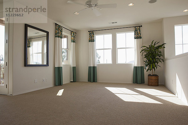 Leeres Zimmer mit Teppich auf dem Boden und Vorhängen an den Fenstern zu Hause