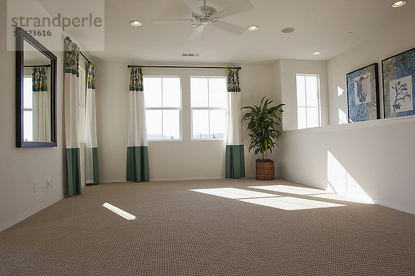 Leeres Zimmer mit Teppich auf dem Boden und Vorhängen an den Fenstern zu Hause