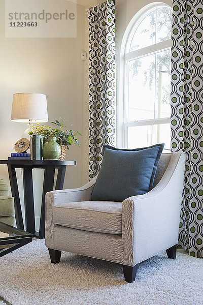 Gepolsterter Sessel mit Beistelltisch am Fenster zu Hause