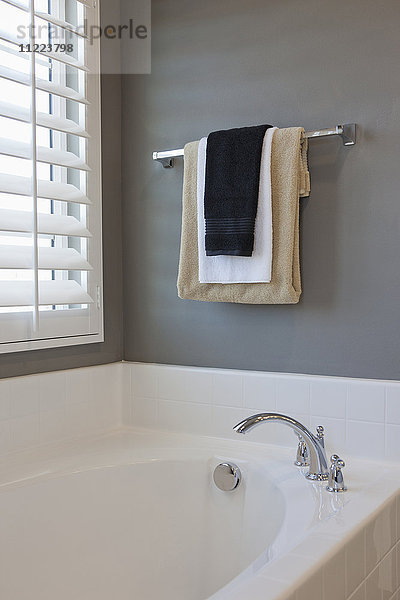 Handtuchhalter und Badewanne am Fenster im häuslichen Badezimmer