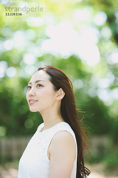 Junge japanische Frau umgeben von Grün in einem Stadtpark