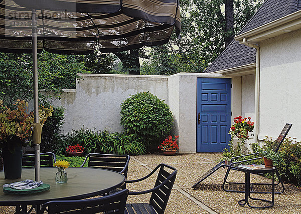 Hofbereich mit hohen Stuckwänden  hellblauer Tür und Terrassenmöbeln